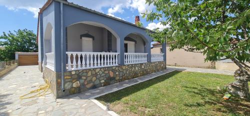 a blue house with a stone wall and a yard at Fertoun apartment in Chaïdeftón