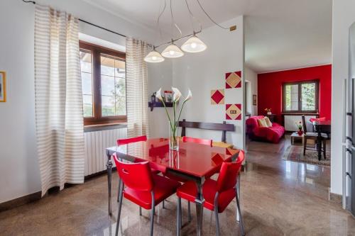 a dining room with a red table and red chairs at Villa Tra Vigne e Stelle in Neive