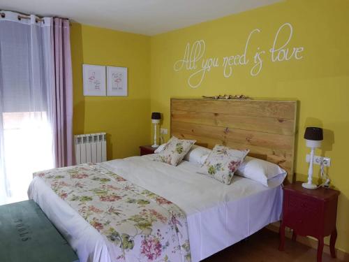 a bedroom with a bed and a sign that reads all you need is love at CasaMarichelvas in San Asensio