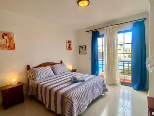 a bedroom with a bed and a window with blue curtains at Casa Inma Las Piteras. Sol y agua in Costa Teguise