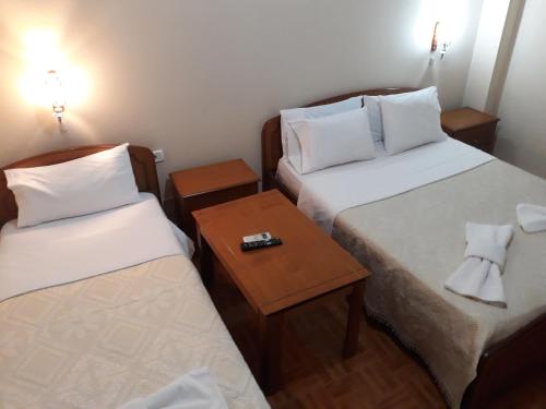 Kleines Zimmer mit 2 Betten und einem Tisch in der Unterkunft Qiqi Hotel in Gjirokastër