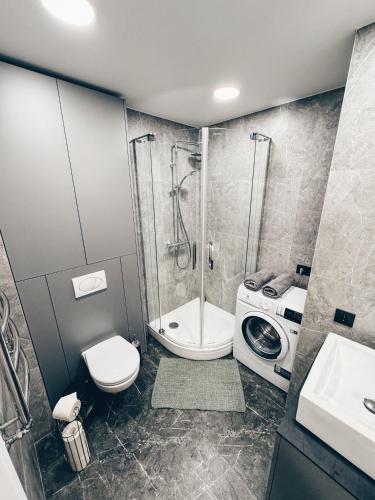 a bathroom with a shower toilet and a washing machine at Sodų apartamentai in Mažeikiai