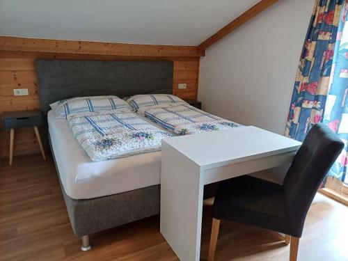 a bedroom with a bed with a table and a desk at Landhaus Eberler in Mayrhofen