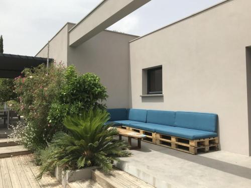 un canapé bleu assis sur le côté du bâtiment dans l'établissement Bungalow, à Sorède
