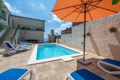 Una piscina con una sombrilla y sillas naranjas y un patio. en Apartment Marina on the second floor, en Makarska