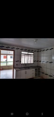 eine Küche mit weiß gefliesten Wänden und 2 Fenstern in der Unterkunft Alojamentos in Telêmaco Borba