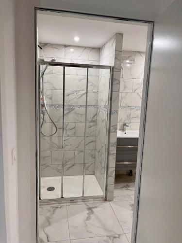 une douche en verre dans une salle de bain avec un lavabo dans l'établissement Maison 5 couchages bien située, à Marseille