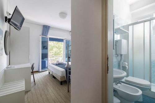 a bathroom with a sink toilet and a bedroom at Hotel Danieli in Lido di Jesolo