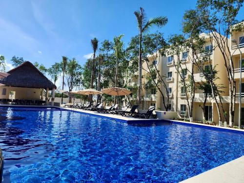 a large blue swimming pool with chairs and umbrellas at Depa en Playa 7min Mar y 5ta Av in Playa del Carmen