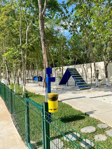 a playground with a blue and yellow slide in a park at Depa en Playa 7min Mar y 5ta Av in Playa del Carmen