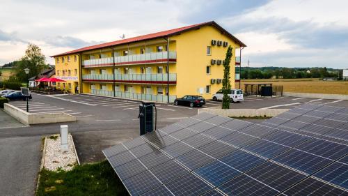 un edificio con paneles solares frente a un aparcamiento en Hotel Vulkan Residenz - Self-Check-in, en Leibnitz