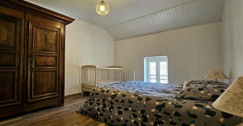 - une chambre avec un lit et une grande armoire en bois dans l'établissement Maison Saint Côme du Mont, à Saint-Côme-du-Mont