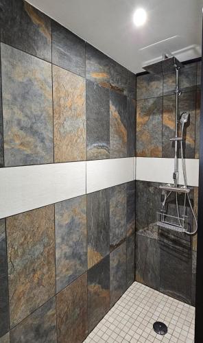 La salle de bains est pourvue d'un mur carrelé et d'une douche. dans l'établissement Maison Saint Côme du Mont, à Saint-Côme-du-Mont