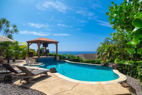 a swimming pool with chairs and a gazebo at Kailua-Kona Exceptional Oceanview Home - Heated Oasis Pool & Stunning Ocean View in Kailua-Kona