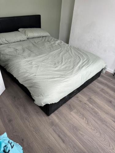an unmade bed in a bedroom with a wooden floor at High street home in Eastleigh