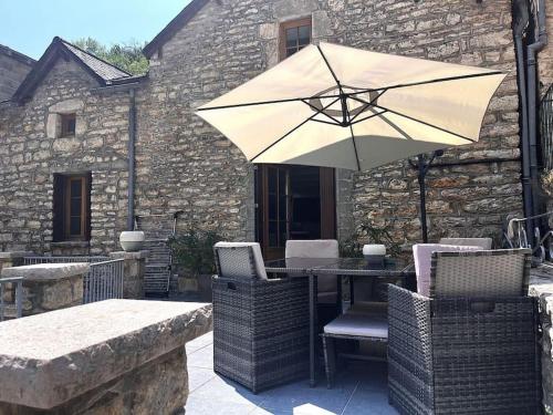 a table and chairs with an umbrella on a patio at Gîte de la Bergère in La Malène