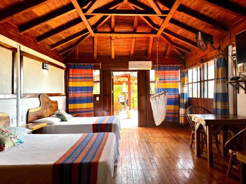 a room with two beds and a table and windows at Casa Paraiso Hotel Boutique in Puerto Escondido