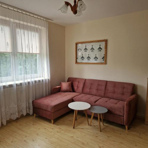 a living room with a red couch and two tables at Apartament Sybiraków in Białystok