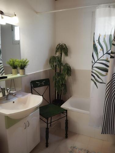 a bathroom with a sink and a chair next to a tub at Raxoni House in Skala Rachoniou