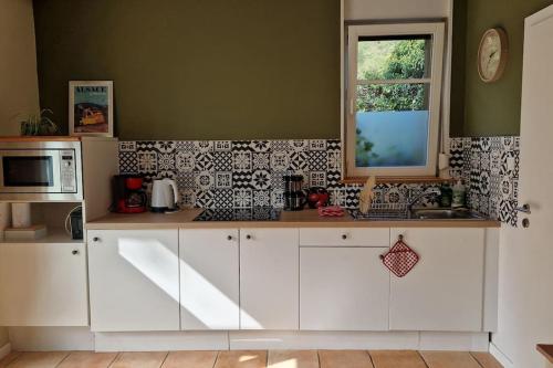 une cuisine avec des armoires blanches et une fenêtre dans l'établissement Appartement Le Petit Vadrouilleur, à Ribeauvillé
