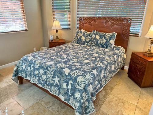 a bedroom with a bed with a blue and white comforter at Kailua-Kona Exceptional Oceanview Home - Heated Oasis Pool & Stunning Ocean View in Kailua-Kona