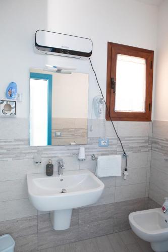 a bathroom with a sink and a mirror and a toilet at La Casa del Corso in Orgosolo