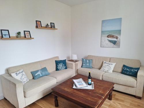 a living room with two couches and a coffee table at Appartement au cœur de la Côte de Granit Rose. in Trégastel