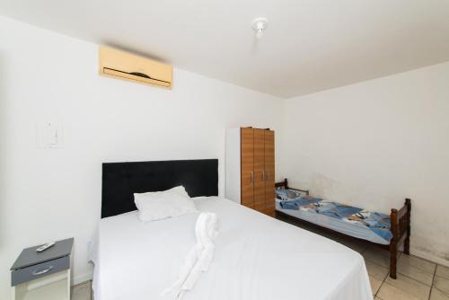 a bedroom with a white bed and a wooden cabinet at Casa Espaçosa com quintal interno in Palhoça