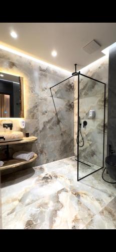 a bathroom with a shower and a stone wall at Hotel Joni Premium in Ksamil
