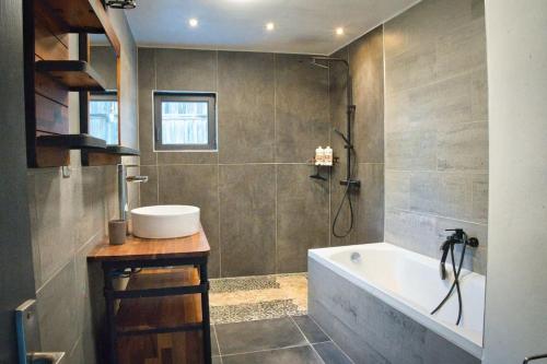 une salle de bain avec une baignoire et un lavabo dans l'établissement Maison atypique avec piscine 