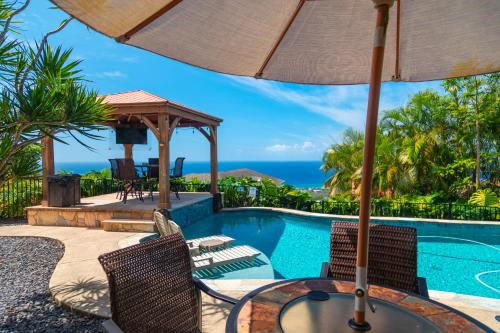 a patio with a table and chairs next to a swimming pool at Kailua-Kona Exceptional Oceanview Home - Heated Oasis Pool & Stunning Ocean View in Kailua-Kona