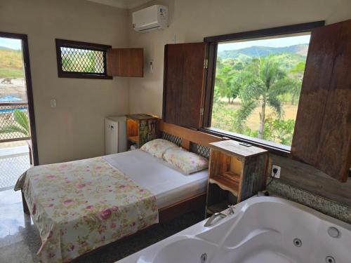 um quarto com uma cama, uma banheira e uma janela em Pousada Fazenda do Prata Ecoresort em Caratinga