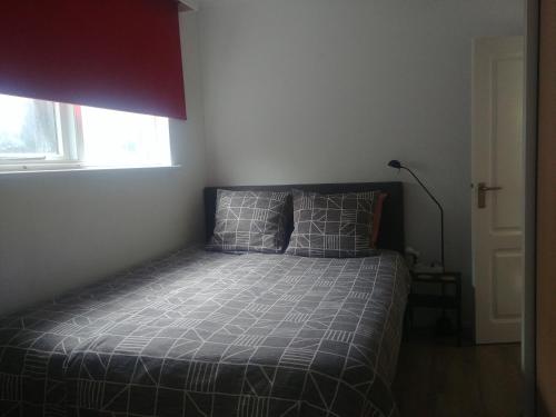 um quarto com uma cama com um edredão cinzento e uma janela em Gastvrij verblijf in gezellig dorp dichtbij natuur em Enter