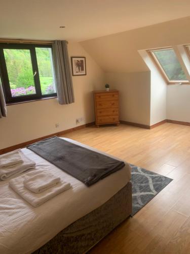 a bedroom with a bed and a dresser and windows at Captivating 5-Bed Cottage with private hot tub in Spean Bridge