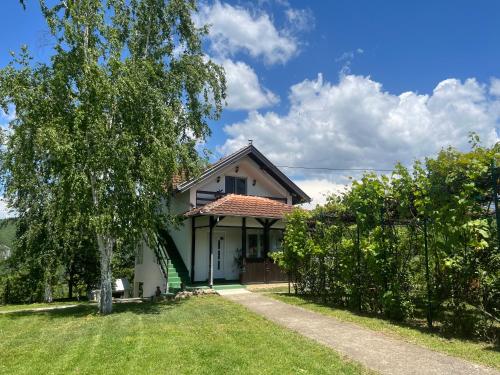 a white house with a tree and a fence at Villa Buena in Despotovac