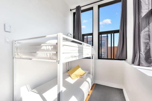 ein Etagenbett in einem weißen Raum mit Fenstern in der Unterkunft M11 The Simpsons Suite 3BR in The Heart of MTL in Montreal