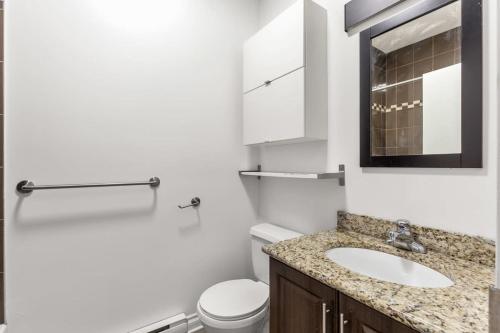 ein Badezimmer mit Waschbecken, Toilette und Spiegel in der Unterkunft M11 The Simpsons Suite 3BR in The Heart of MTL in Montreal
