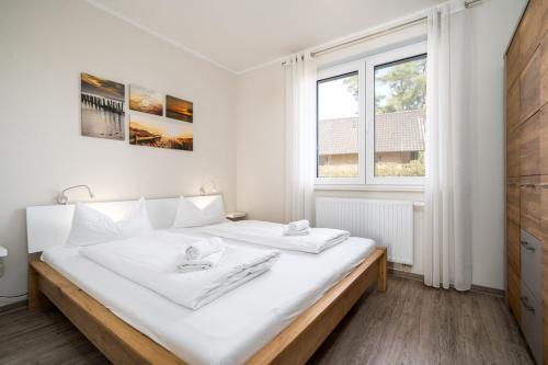 a white bedroom with a large bed with white sheets at Strandhaus 1 EG in Marienfelde