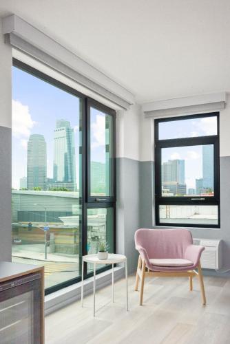 a living room with a pink chair and a large window at The Metric - Los Angeles Downtown in Los Angeles