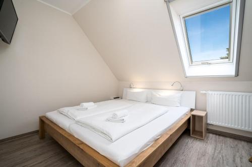 a bedroom with a large white bed with a window at Strandhaus 3 OG in Marienfelde