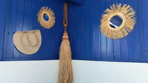 a straw hat and a straw broomstick hanging on a blue door at Riad Al Manara in Essaouira
