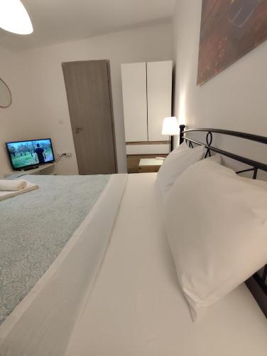 Schlafzimmer mit einem Bett mit weißer Bettwäsche und einem TV in der Unterkunft Johnson House in Rafina