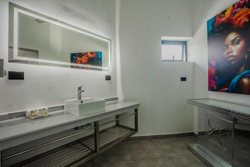 a bathroom with a sink and a painting on the wall at Instyle Residences at RIZZ SUITES in Sosúa
