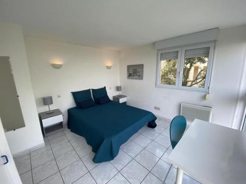 Un dormitorio con una cama azul y una mesa. en L'appartement des Albères, en Laroque-des-Albères