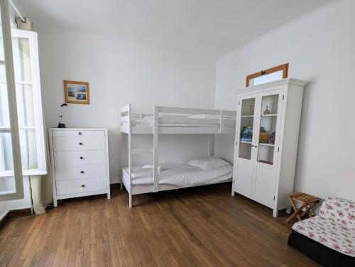 a bedroom with white bunk beds and a dresser at Charmante Maison au centre-ville in Pornic