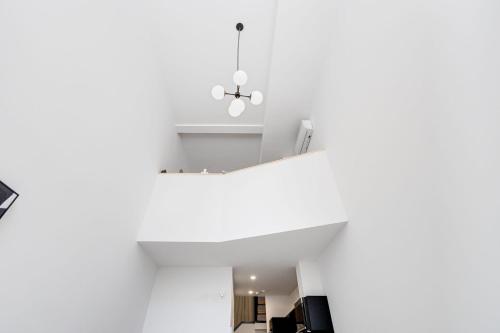 a room with white walls and a ceiling with a chandelier at Le Mile End by M11 - Modern Luxe 1BDR with Sofa Bed in Montréal