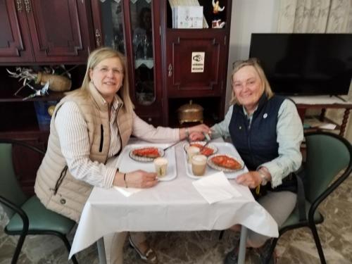 zwei Frauen sitzen an einem Tisch und essen Essen in der Unterkunft Pensión Casa do Gallo Sarria in Sarria