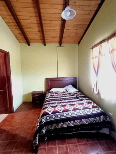 a bed in a bedroom with a wooden ceiling at Cosme Andres Pujilí in Pujilí