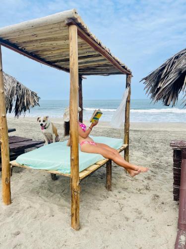 a woman laying on a bed on the beach with a dog at Un Dia Boutique Resort in Playas