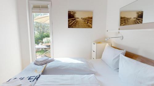 a white bedroom with a bed and a window at Feriendorf Südstrand Haus 23 in Pelzerhaken